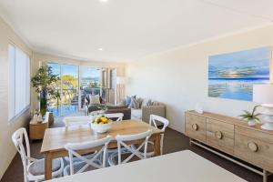 a dining room with a table and chairs and a living room at Baywatch 3 in Merimbula