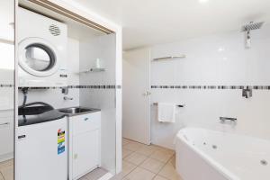 a white bathroom with a sink and a tub at Baywatch 3 in Merimbula +16 photos