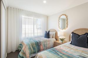 a bedroom with two beds and a mirror at Baywatch 3 in Merimbula