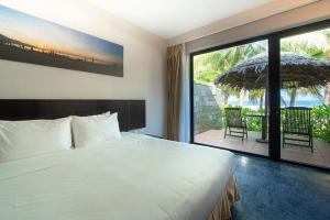 a bedroom with a bed and a balcony with an umbrella at Temple Beach Resort in Danang