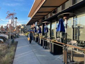 a person walking down a sidewalk next to a building with blue umbrellas at Almost Home in West Vancouver
