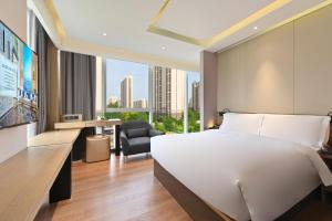 una camera da letto con un letto, una scrivania e una sedia di Jingli Hotel Beijing Heshenghui Dajiaoting Subway Station Branch a Pechino