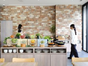 东京hotel MONday Haneda Airport的两个人站在厨房里，厨房台面上摆着餐具。 更多91张照片