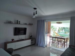 a living room with a tv and a sliding glass door at Imbassaí in Imbassai