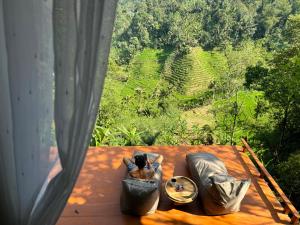 a woman sitting on a bed looking out of a window at aforest at True Bali Villa in Blimbing