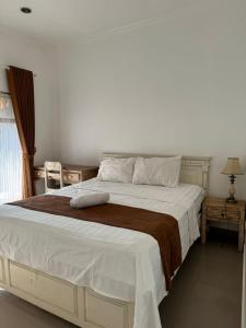 une chambre avec un grand lit avec une couverture marron dans l'établissement ATHAYA GUEST HOUSE canggu, à Kerobokan