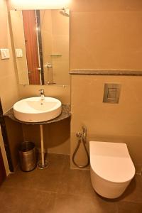 哈桑Poorva Residency的带水槽、马桶和镜子的浴室