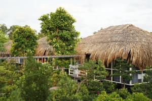 un resort con tetto di paglia e alberi di Resort Thái An a Cai Be