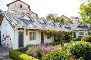 a house with a garden with flowers in front of it at La nha Homestay in Da Lat