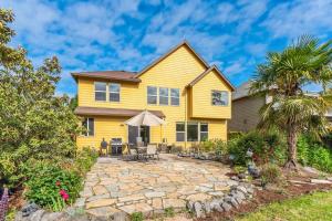 a yellow house with a stone patio and palm trees at Spacious, Quiet, private, 5 BR Near Portland DT in Beaverton