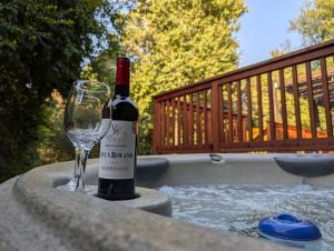 a bottle of wine and a glass sitting next to a hot tub at Sequoia Zen River House in Three Rivers