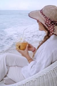 Eine Frau, die am Strand sitzt und einen Drink isst. in der Unterkunft Selenya Talpe - Boutique Villa in Unawatuna