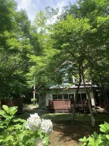 a house with a bench and trees in front of it at clover house in Nasu