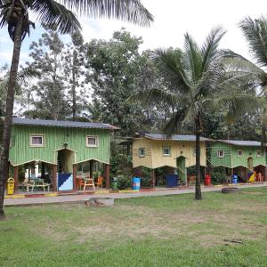 a green and yellow house with palm trees at Farmers Son CampingGround in Sakleshpur