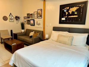 a bedroom with a large white bed and a couch at BGC 1BR unit linked to Uptown Mall with own parking in Manila