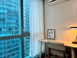 a desk with a chair in front of a window at BGC 1BR unit linked to Uptown Mall with own parking in Manila