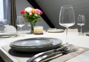 a table with a plate and two wine glasses and flowers at CASA LUXE - 80qm - Stadtmitte - Familienfreundlich - Parkplatz - 5km zum Legoland in Günzburg