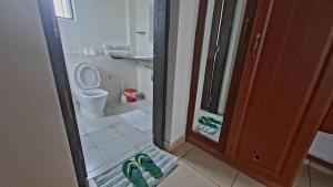 ein Badezimmer mit Toilette und einem Paar grüne Schuhe in der Unterkunft Ary Homestay - On 5th Avenue in Nyali