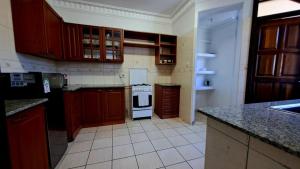 eine Küche mit Holzschränken und einem weißen Kühlschrank in der Unterkunft Ary Homestay - On 5th Avenue in Nyali + 19 Fotos