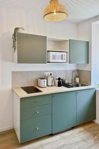 Una cocina con gabinetes azules y un microondas. en Une touche de vert, en Mulhouse
