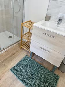 y baño con lavamanos, ducha y alfombra. en Une touche de vert, en Mulhouse