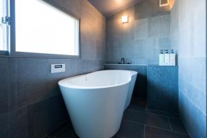 una vasca bianca in un bagno con finestra di 由良民泊島宿 a Matsuyama Altre 29 foto