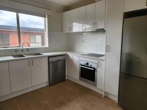 a kitchen with white cabinets and a sink and a dishwasher at Cosy & Convenient Williamstown in Williamstown