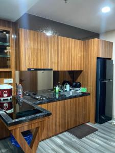 a kitchen with a black counter top and wooden cabinets at Casapedian 010 Vasaka Reiz Condo 1 BR in Medan