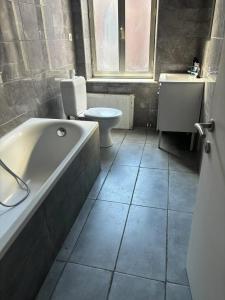 a bathroom with a tub and a toilet and a sink at Charming House in Sclessin, Liège with Terrace in Tilleur