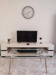 a white table with a tv and a clock on a wall at Apartment by the beach truman 8-1 in Qiryat H̱ayyim