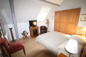 a bedroom with a bed and a tv in it at Manoir de la Croix-Sonnet in Trouville-sur-Mer