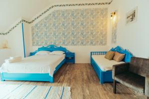 a blue bedroom with two beds and a chair at La Navod Jurilovca in Jurilovca