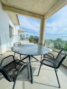 a glass table and two chairs on a balcony at Coral Bay Garden in Peyia