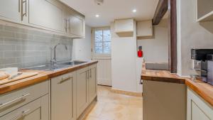 a kitchen with white cabinets and a sink at Spinner's Cottage in Burford