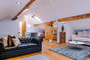 a living room with a black leather couch and a table at The Loft Apartments | Cheadle in Cheadle Hulme