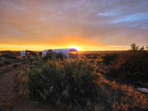 a sunset in the middle of a field with two rvs at Groot Gryses Adam Se Uitspanning in Orania