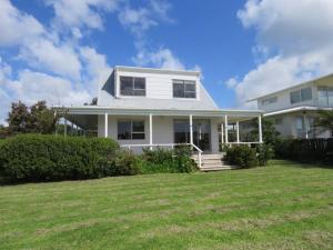 a white house with a lawn in front of it at Raines Retreat - Taipa Beach Bach in Taipa