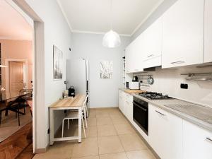 a kitchen with white cabinets and a wooden table at La tua casa nel cuore di Torino in Turin