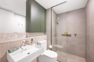 a bathroom with a toilet and a sink and a shower at Central located 2 bedroom Apartment in Canberra with Parking in Canberra +2 photos