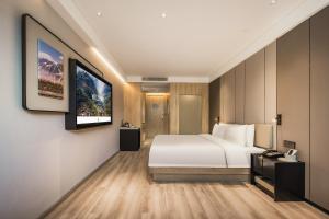 a hotel room with a white bed and a flat screen tv at Atour Hotel -Du Fu Thatched Cottage in Chengdu
