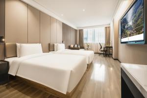a hotel room with two beds and a flat screen tv at Atour Hotel -Du Fu Thatched Cottage in Chengdu