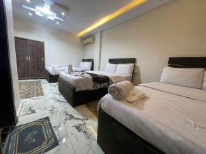 Una habitación de hotel con tres camas y toallas. en Pyramids High View Inn, en Giza