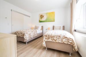 2 camas en un dormitorio con paredes blancas y suelo de madera en Luxury Zweibrücken 1, en Zweibrücken