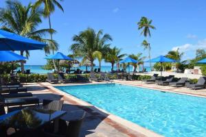 a swimming pool with chairs and umbrellas and the ocean at Relax at Private beach, Pools, Acuatic Park & more in Bayahibe +19 photos