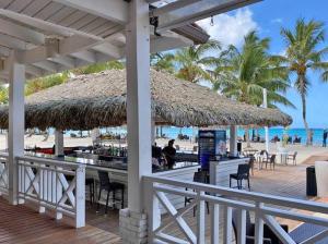 a beach bar with a straw umbrella and tables and chairs at Relax at Private beach, Pools, Acuatic Park & more in Bayahibe