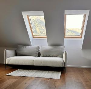 a couch in a living room with two windows at Nordic Sun 01 in Kranjska Gora