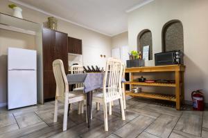 a kitchen with a table and chairs and a refrigerator at Solo Gracia Guesthouse in Bloemfontein