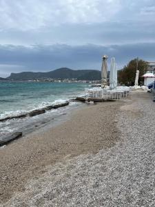 a group of chairs and umbrellas on a beach at Seafront Porto Rafti, 95 sq m close to airport, garden in Agios Spyridon