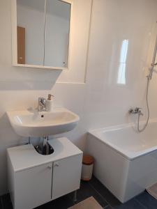 a white bathroom with a sink and a bath tub at Ferienwohnung Weitblick in Dachau +11 photos