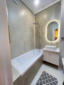 a bathroom with a tub and a sink and a mirror at Bravo Family apartment in Promyshlennyy +10 photos